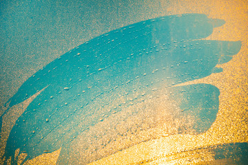 Close-up imprints of the fingers on the water dust sprayed window. Blue shades mixing with orange shades of shining sunset light. Ideal background for illustrations, collages. Artistic retouching.