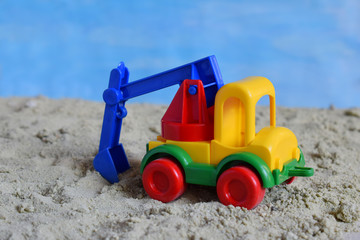Conceptual photo picture of plastic car in desert. Children's toy. Children play in the sand. The concept of a happy childhood. Kids toys excavator