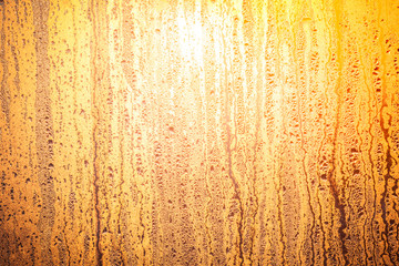Bright sun shinning through the glass window. Sunrise in yellow orange tawny tints. The drops of water on the glass surface. Ideal background for the illustrations and collages.