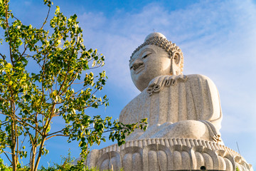 Low angle view of white marble big Buddha statue on top of the hill in evening with blue sky...