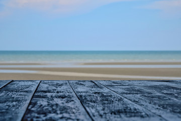 View of sand beach and sea and blue sky with the wooden table. Relax and vacation concept.