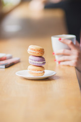 French colored macarons on the plate and a cup of coffee