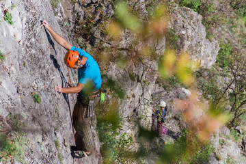 Young man lead climbing on cliff