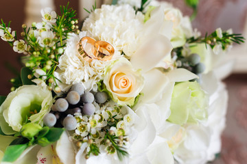 close-up of beautiful golden wedding rings that lie on a delicate wedding bouquet