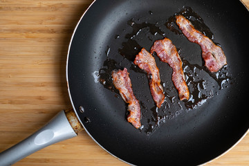 slices of fresh fried bacon in a pan for breakfast