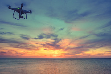 quadrocopter drone with remote control. Dark silhouette against colorfull sunset. Soft focus. Toned image