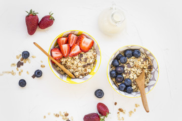 Muesli bowls with strawberries, blueberries fruits and milk , flatlay of healthy breakfast bowls