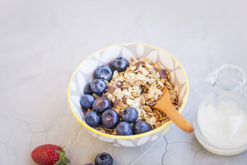 Bowl of muesli with blueberries fruits, healthy breakfast with oatmeal, milk and fruits