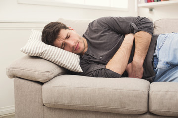 Young man having stomachache at home