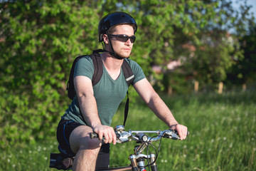 Young man sitting on his bike in nature,and drinking water