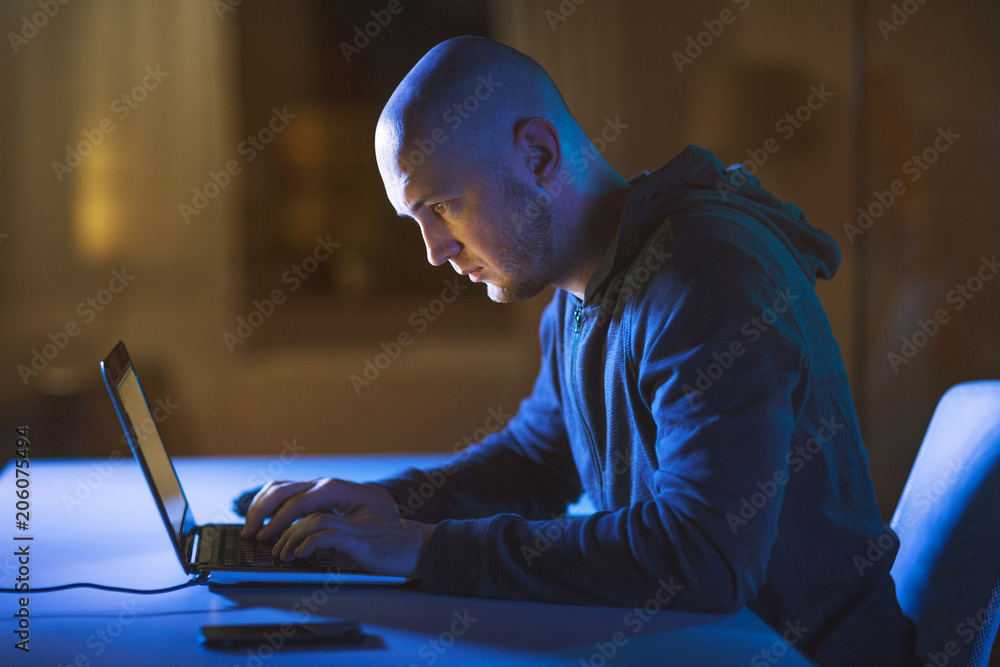 Aufkleber cybercrime, hacking and technology crime - male hacker in dark room using laptop computer for cyber 