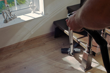hand with vacuum cleaner in the apartment near the stairs