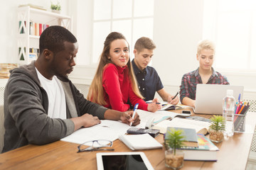 Group of diverse students studying at wooden table