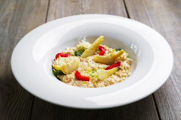 Healthy breakfast, restaurant menu photo, diet food. Chef's creamy oatmeal with artichokes and dried tomatoes, delicious meals with proteins and low fat.