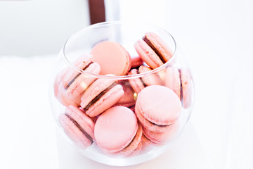 A close-up of delicious pink macaroons in a transparent glass bowl