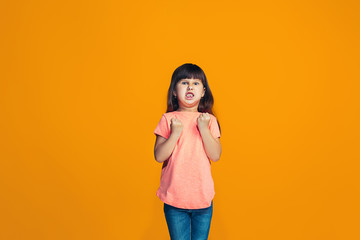 Portrait of angry teen girl on a orange studio background