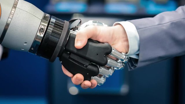 Hand of a businessman shaking hands with a Android robot.