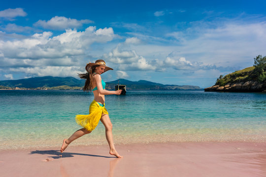 Full length of a fashionable young woman enjoying happiness and freedom while walking on a tropical beach during summer vacation in Komodo Island, Indonesia