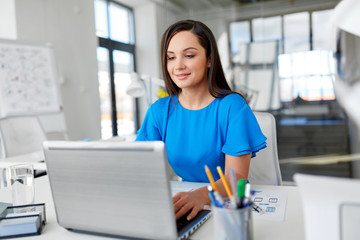 business, technology and people concept - businesswoman with laptop computer working at office