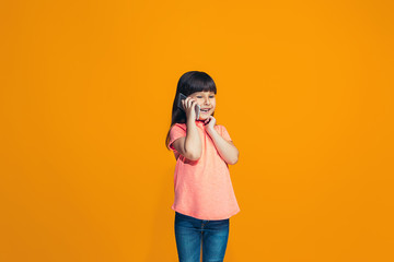 Obraz premium The happy teen girl standing and smiling against orange background.