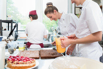 Three pastry bakers in confectionary preparing fruit pies for later sale © Kzenon
