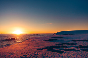 Fototapeta premium The polar sunset sunrise that was shot during the extreme expedition to the Vernadsky Research Base. Stunning snow landscape the icy Antarctic surface and Pacific Ocean.