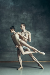 Fototapeta na wymiar The young modern ballet dancers posing on gray studio background