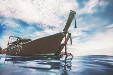 Close-up colorful ribbon decorated bow of the traditional fishing wooden boat in the ocean next to the exotic Phi Phi Islands, the Kingdom of Thailand. Spectacular cloudy blue sky background. © Goinyk