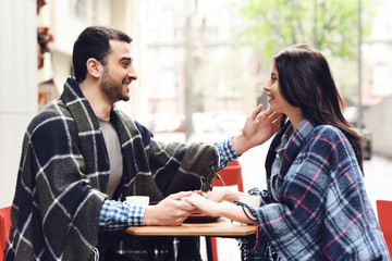 Loving couple in rugs sits at table.