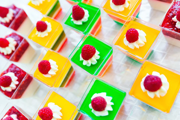 A close-up of an appetizing colored jelly with cream and raspberry