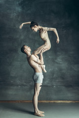 The young modern ballet dancers posing on gray studio background