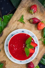 Fresh raw strawberry mint dessert for breakfast. Fruit yoghurt or smoothie on wooden board. Fruit jam mixed with blender. Raw vegan vegetarian healthy food