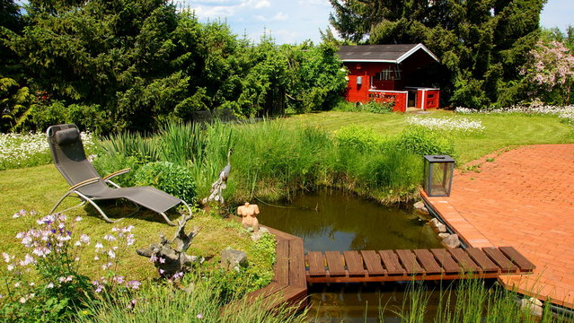 naturbelassener Gartenteich mit Brücke und Margeritenwiese sowie Terrasse und Gartenhaus