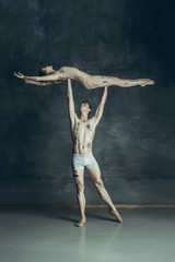 Fototapeta na wymiar The young modern ballet dancers posing on gray studio background