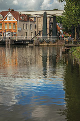 Clouds and sky reflected in canal water surface, buildings and bascule bridge on a sunny day in Weesp. Quiet and pleasant village full of canals and green near Amsterdam. Northern Netherlands.