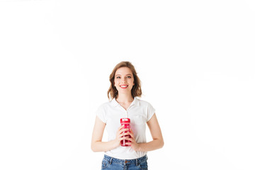 Portrait of young beautiful lady standing with pink sport bottle in hands and happily looking in camera on white background isolated.