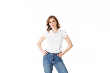 Portrait of young beautiful lady standing in t shirt and jeans and dreamily looking in camera on white background isolated