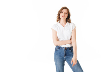 Obraz premium Portrait of young pensive lady standing in t shirt and jeans and thoughtfully looking in camera on white background isolated