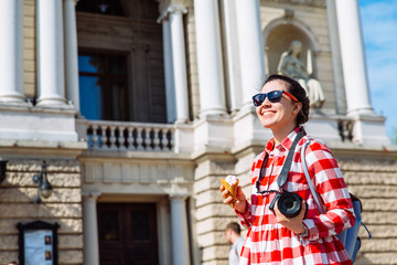 Fototapeta premium woman walking by city with camera and ice cream. copy space