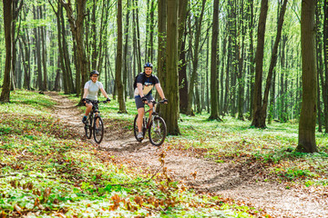 Obraz premium couple riding bicycle in forest in warm day