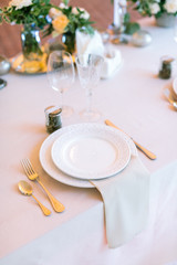 feast, celebration, party concept. there is a close up of place of the restaurant for one person, served with elegant silverware and dishes, decorated with napkin and card for a name of guest