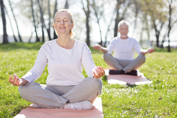 Mental health. Pleasant aged woman feeling peaceful while practicing yoga