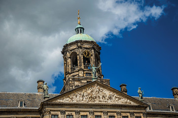 Fototapeta na wymiar Close-up of facade with sculptures and dome with golden clock in the Royal Palace of Amsterdam. The city is famous for its huge cultural activity, graceful canals and bridges. Northern Netherlands.
