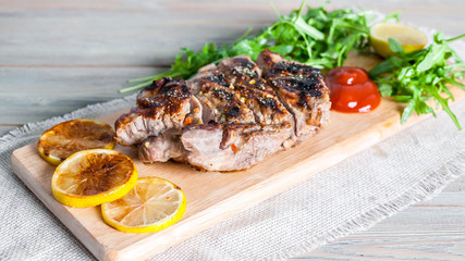 Grilled turkey fillet, spices and fresh arugula on a wooden background. Banner. Selective focus