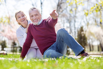 Look there. Delighted aged man pointing with his hand while showing something interesting to his wife