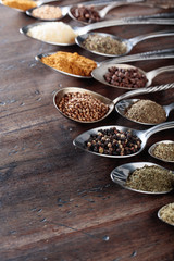 Different spices in  spoons on a wooden background.