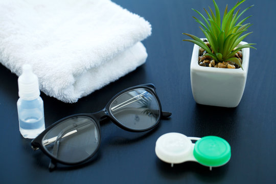 Glasses and objects for cleaning and storing contact lenses, to improve vision, on a black background