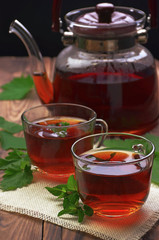 Cup of mint tea and leaves of mint on the table. Herb tea. Healing herbs. A cup of tea and a teapot. Tea time. Break. Relaxation.