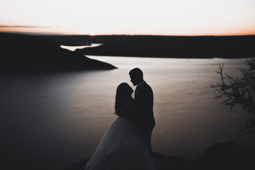 Wedding couple, groom, bride posing near sea on sunset