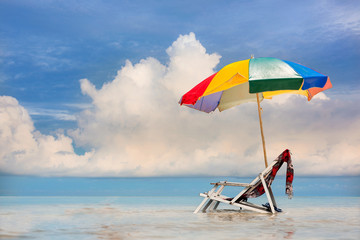deck couch beach chair and woman shawl with gamp umbrella stay together in middle part of the sea water, beautiful and blue in background